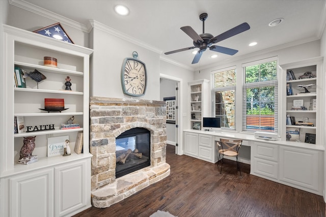 office area with ceiling fan, built in shelves, dark wood-type flooring, ornamental molding, and a fireplace