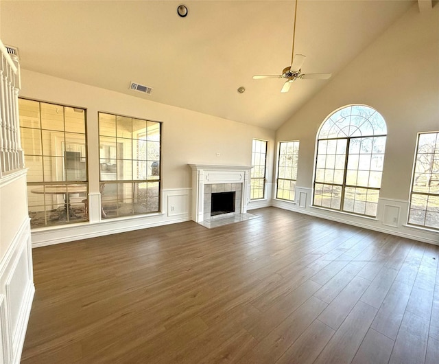 unfurnished living room with ceiling fan, high vaulted ceiling, visible vents, dark wood-style floors, and a tiled fireplace