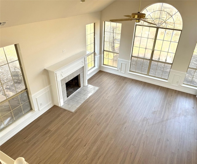 unfurnished living room featuring visible vents, ceiling fan, vaulted ceiling, wood finished floors, and a tile fireplace