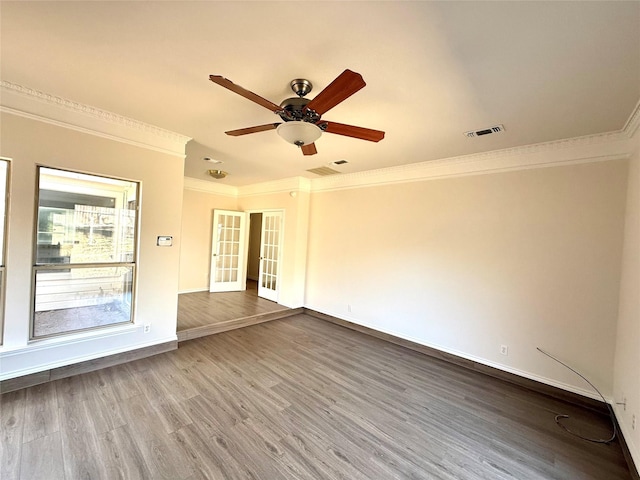 spare room featuring wood finished floors, visible vents, baseboards, french doors, and ornamental molding