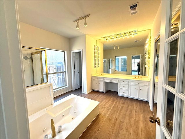 bathroom featuring a whirlpool tub, vanity, wood finished floors, and visible vents