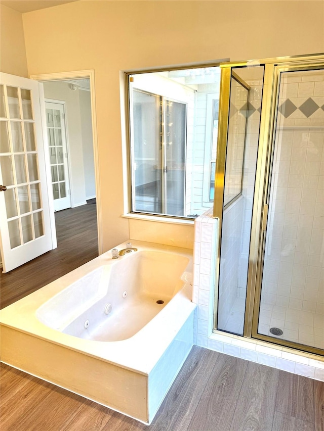 full bathroom with a jetted tub, a shower stall, and wood finished floors