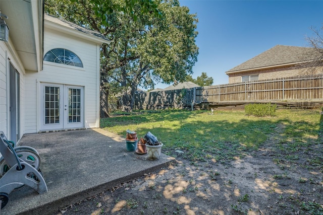 view of yard featuring french doors, a fenced backyard, and a patio