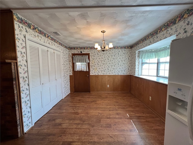 unfurnished dining area featuring dark hardwood / wood-style flooring and an inviting chandelier