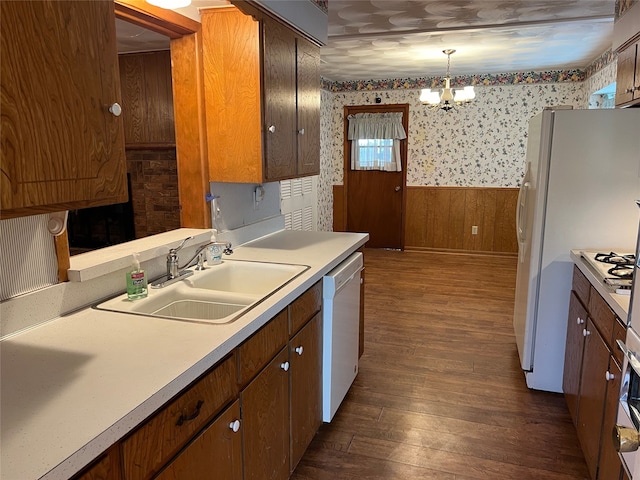 kitchen with dark hardwood / wood-style floors, pendant lighting, a chandelier, white dishwasher, and sink