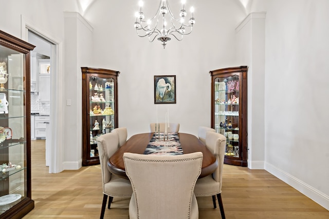 dining space with light wood-type flooring and a notable chandelier