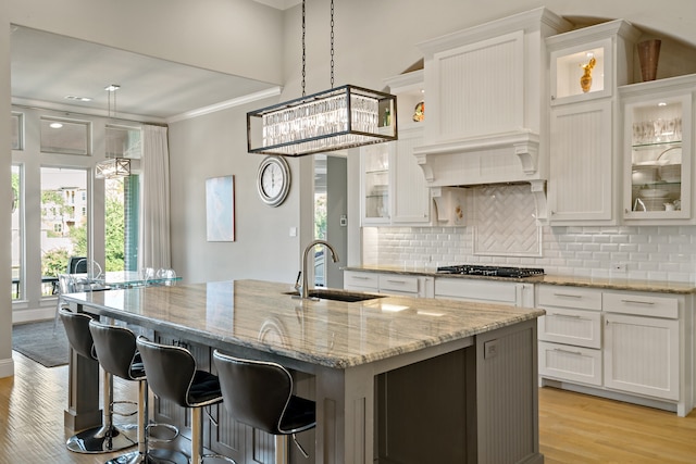 kitchen with an island with sink, sink, and white cabinets