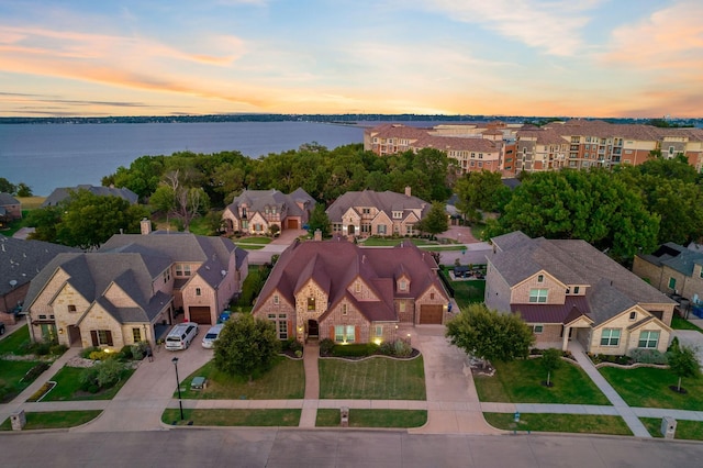 aerial view at dusk featuring a water view