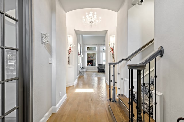 entryway featuring light wood-type flooring, vaulted ceiling, and an inviting chandelier