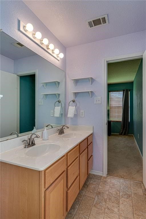 bathroom featuring double vanity, tile patterned flooring, and a textured ceiling