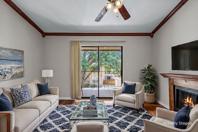 living area with a warm lit fireplace, crown molding, and wood finished floors