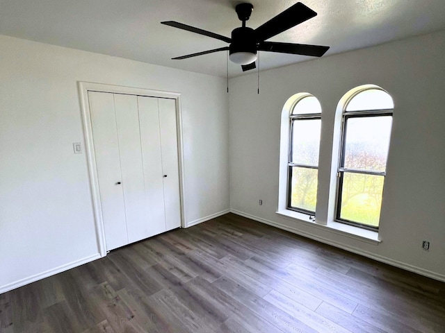 unfurnished bedroom with ceiling fan, a closet, and dark hardwood / wood-style floors