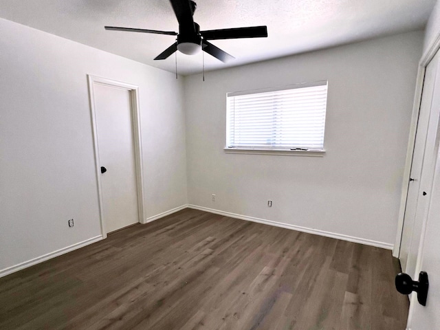 unfurnished bedroom with ceiling fan and dark wood-type flooring