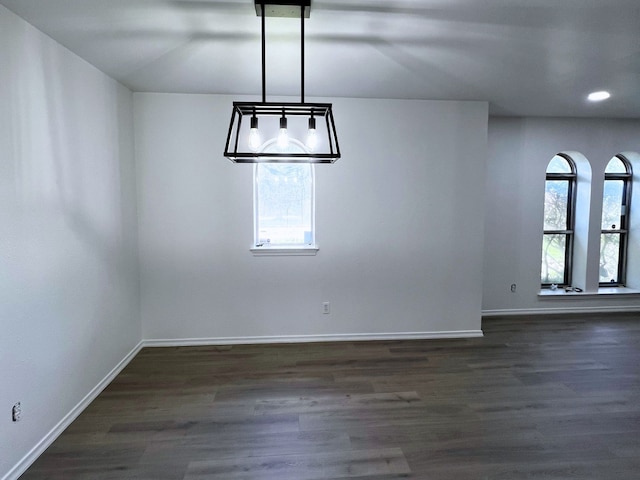 unfurnished dining area featuring an inviting chandelier and dark hardwood / wood-style flooring