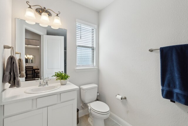 bathroom featuring toilet, vanity, and a chandelier