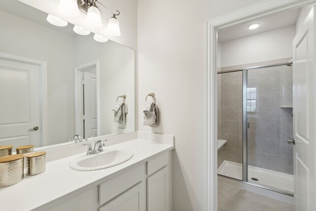 bathroom featuring tile patterned flooring, a shower with shower door, and vanity