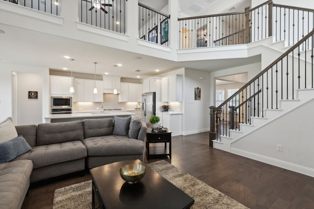 living room featuring a towering ceiling and dark hardwood / wood-style flooring