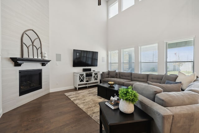 living room featuring a high ceiling, a tile fireplace, and a healthy amount of sunlight