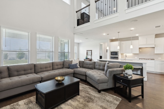 living room featuring sink, a high ceiling, a wealth of natural light, and dark wood-type flooring