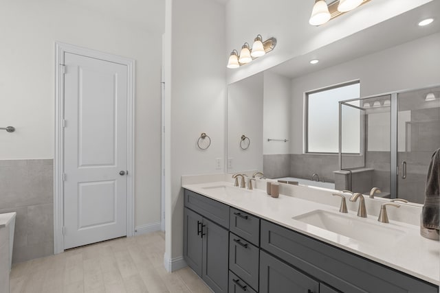 bathroom with wood-type flooring, shower with separate bathtub, vanity, and tile walls