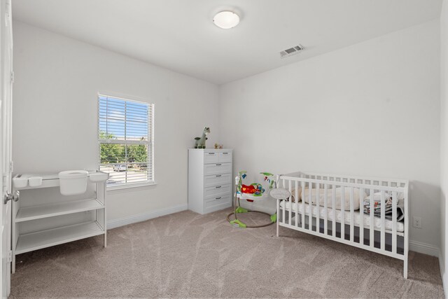 bedroom featuring a crib and carpet