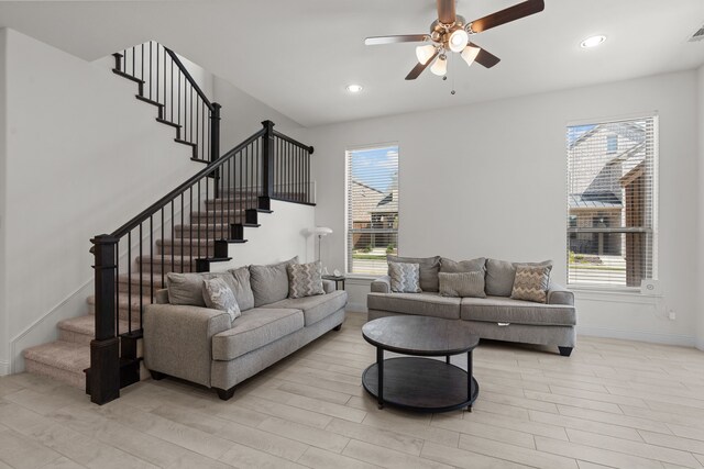 living room with light hardwood / wood-style flooring, ceiling fan, and a healthy amount of sunlight