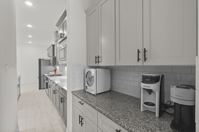 kitchen featuring tasteful backsplash, stainless steel gas stovetop, white cabinetry, light stone countertops, and light tile patterned floors