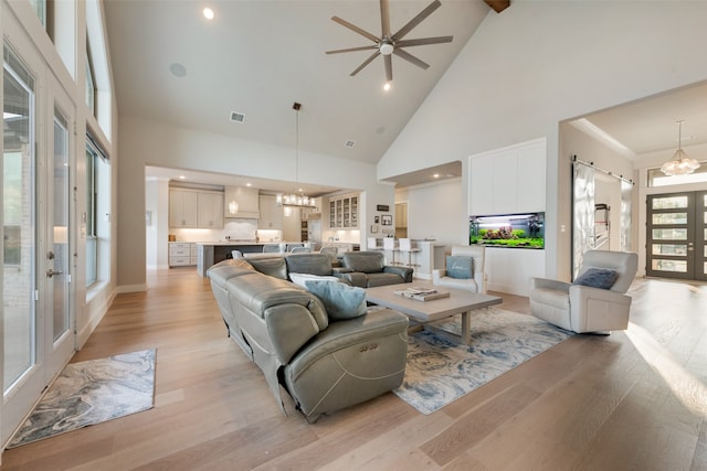 living room featuring light hardwood / wood-style flooring, high vaulted ceiling, ceiling fan with notable chandelier, and crown molding