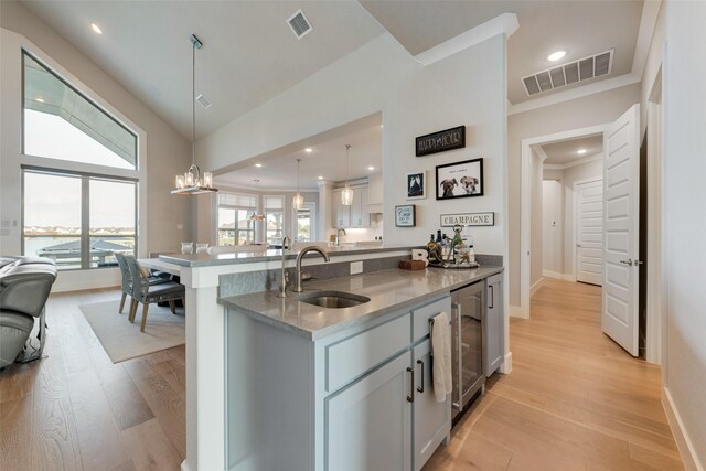 kitchen with sink, kitchen peninsula, decorative light fixtures, light hardwood / wood-style flooring, and an inviting chandelier