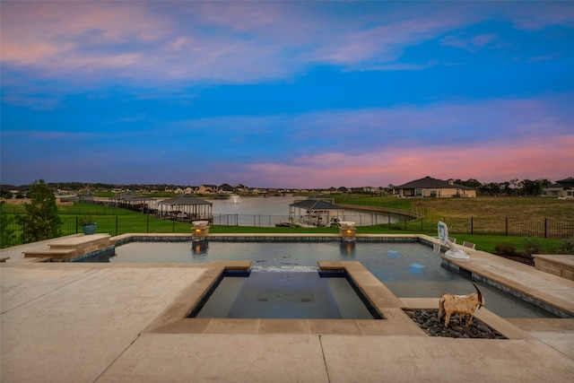 pool at dusk with a gazebo, a yard, and a water view