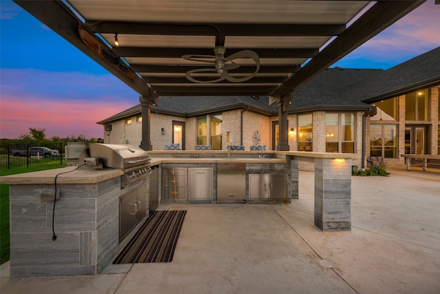 patio terrace at dusk featuring sink, area for grilling, a grill, and ceiling fan