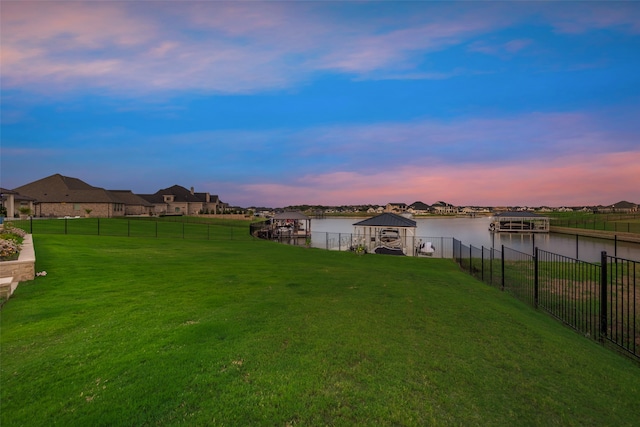 yard at dusk featuring a water view