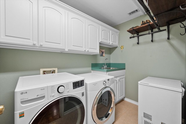 washroom with cabinet space, baseboards, visible vents, washing machine and clothes dryer, and a sink