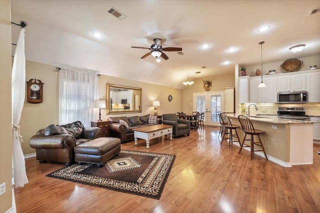 living area featuring lofted ceiling, visible vents, a ceiling fan, french doors, and light wood-type flooring