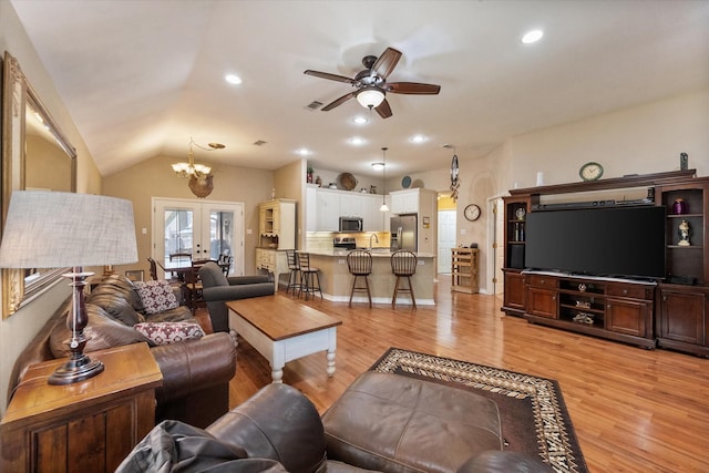 living area with french doors, light wood finished floors, lofted ceiling, recessed lighting, and ceiling fan with notable chandelier