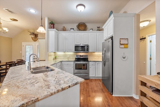 kitchen with white cabinets, decorative light fixtures, a peninsula, stainless steel appliances, and a sink