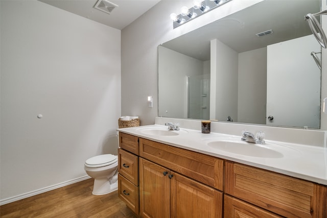 bathroom featuring wood-type flooring, vanity, walk in shower, and toilet