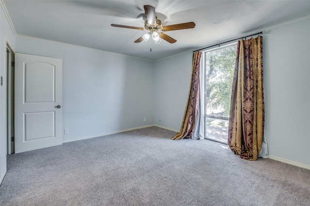 carpeted spare room with a ceiling fan, baseboards, and crown molding