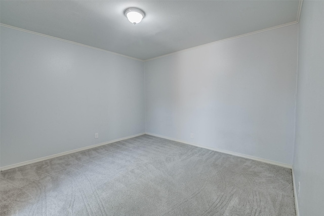 carpeted spare room featuring ornamental molding and baseboards