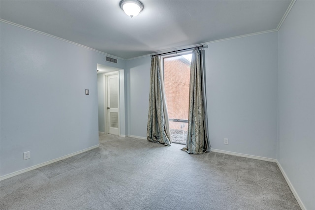 carpeted spare room featuring plenty of natural light, visible vents, baseboards, and ornamental molding