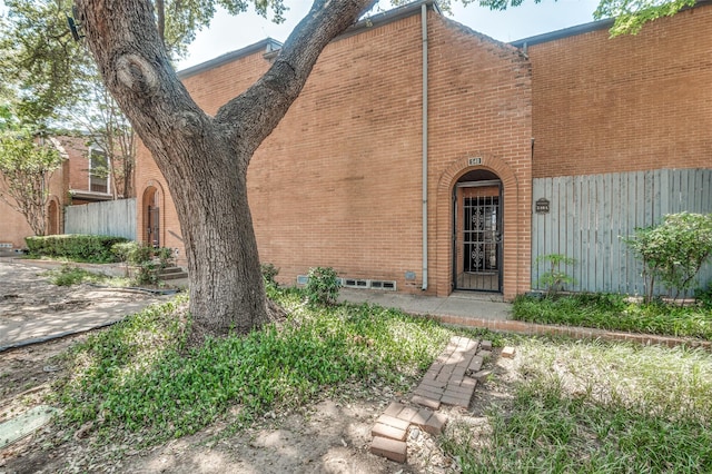 entrance to property featuring fence and brick siding