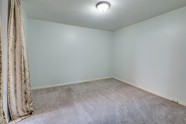 carpeted empty room featuring baseboards and crown molding