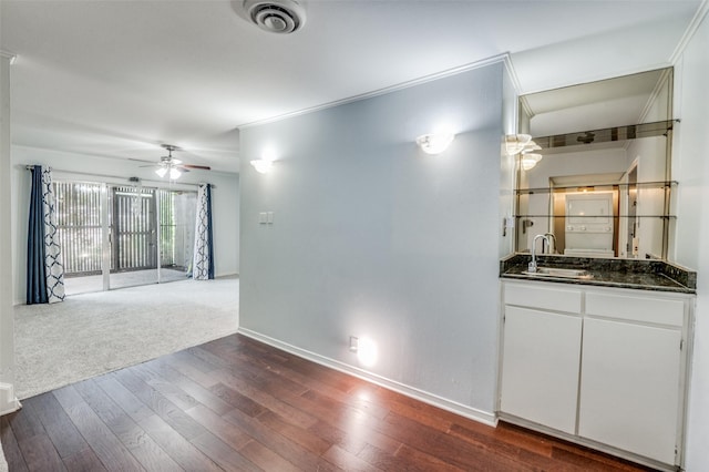 interior space with a sink, a ceiling fan, visible vents, baseboards, and dark wood-style floors