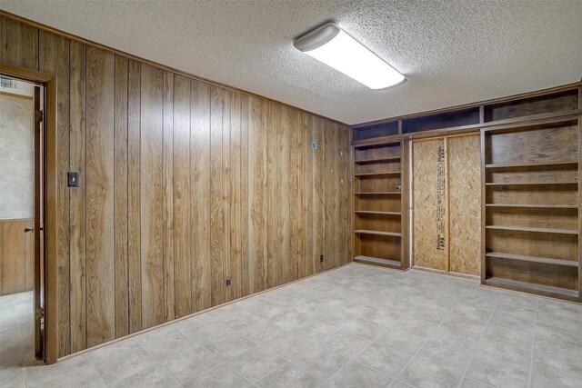 interior space with light tile patterned flooring, a textured ceiling, wooden walls, and built in features