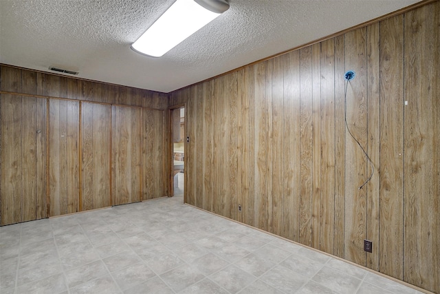 tiled spare room with wood walls and a textured ceiling