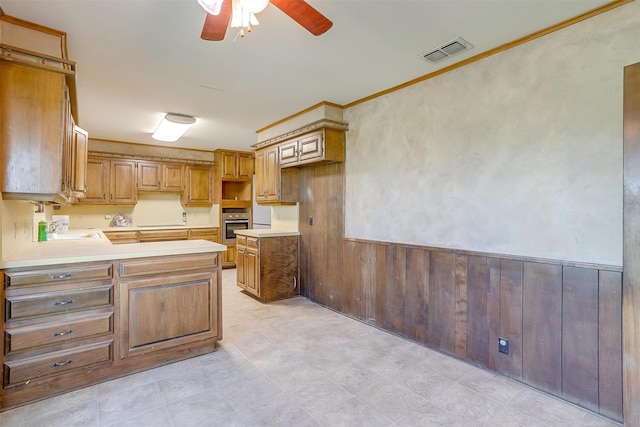 kitchen with ceiling fan, ornamental molding, oven, and light tile patterned floors