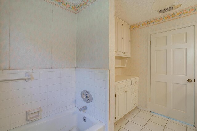 bathroom with shower / bathing tub combination, tile patterned floors, a textured ceiling, vanity, and tile walls