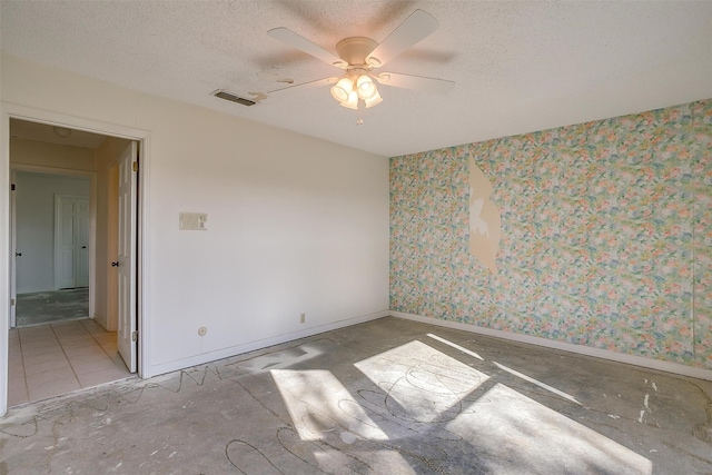 tiled empty room with ceiling fan and a textured ceiling