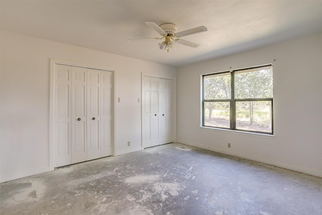 unfurnished bedroom featuring ceiling fan, two closets, and concrete flooring