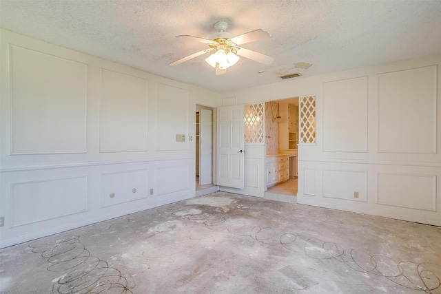 unfurnished bedroom with a textured ceiling, ceiling fan, and ensuite bathroom